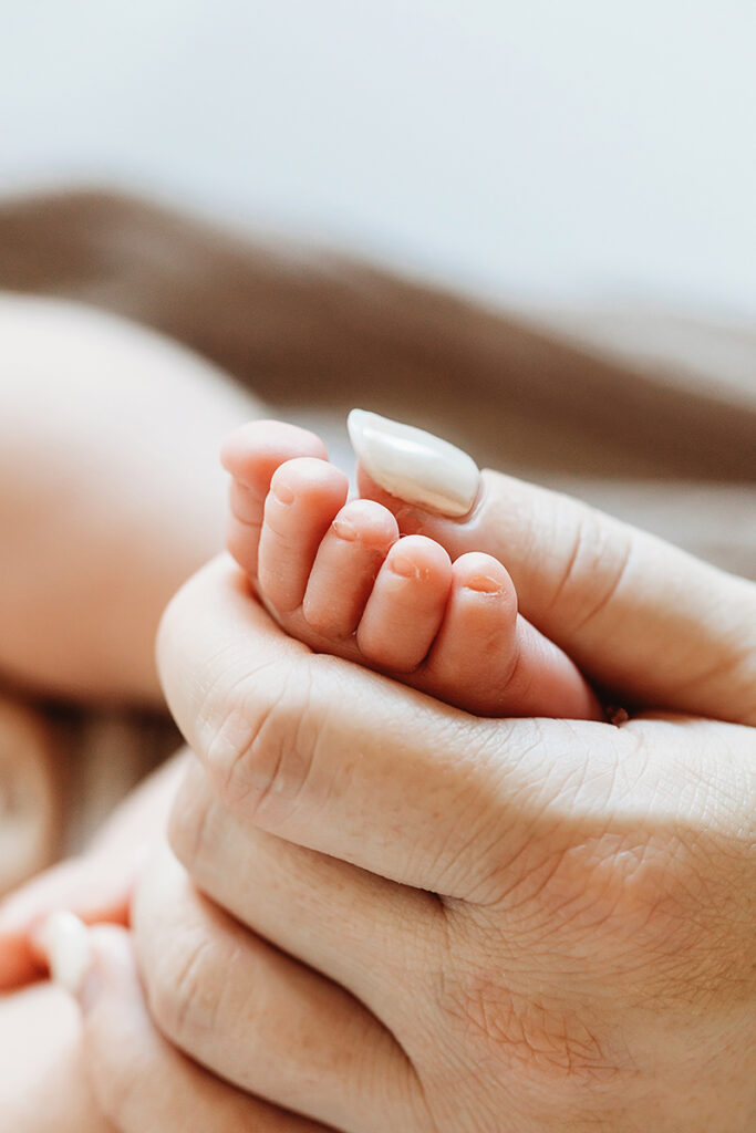 mom holding newborn baby foot