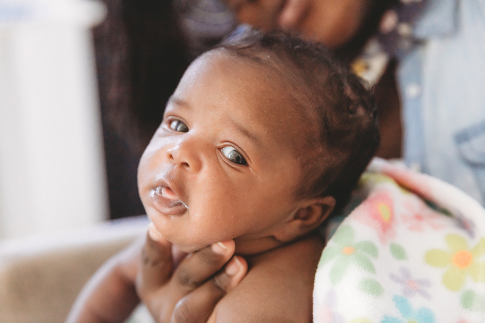 African American newborn Lily awake lifestyle moment held securely by loving hands at Reflection Images by Tracy Rowell in Florence SC