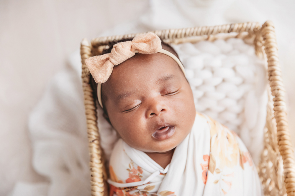 Newborn Lily close crop in the basket, peach bow and chunky knit layer visible at Reflection Images by Tracy Rowell in Florence SC