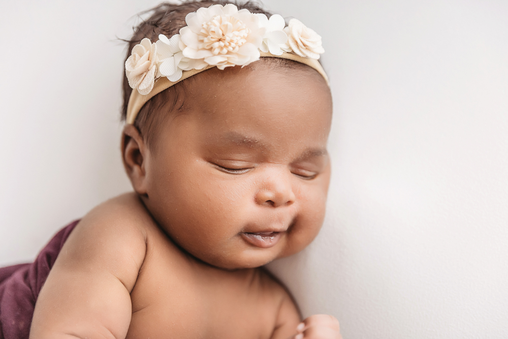 Newborn Lily close up of floral headband and chubby cheek in soft light at Reflection Images by Tracy Rowell in Florence SC