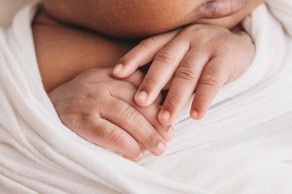 Newborn Lily close up of folded hands resting just under the chin at Reflection Images by Tracy Rowell in Florence SC