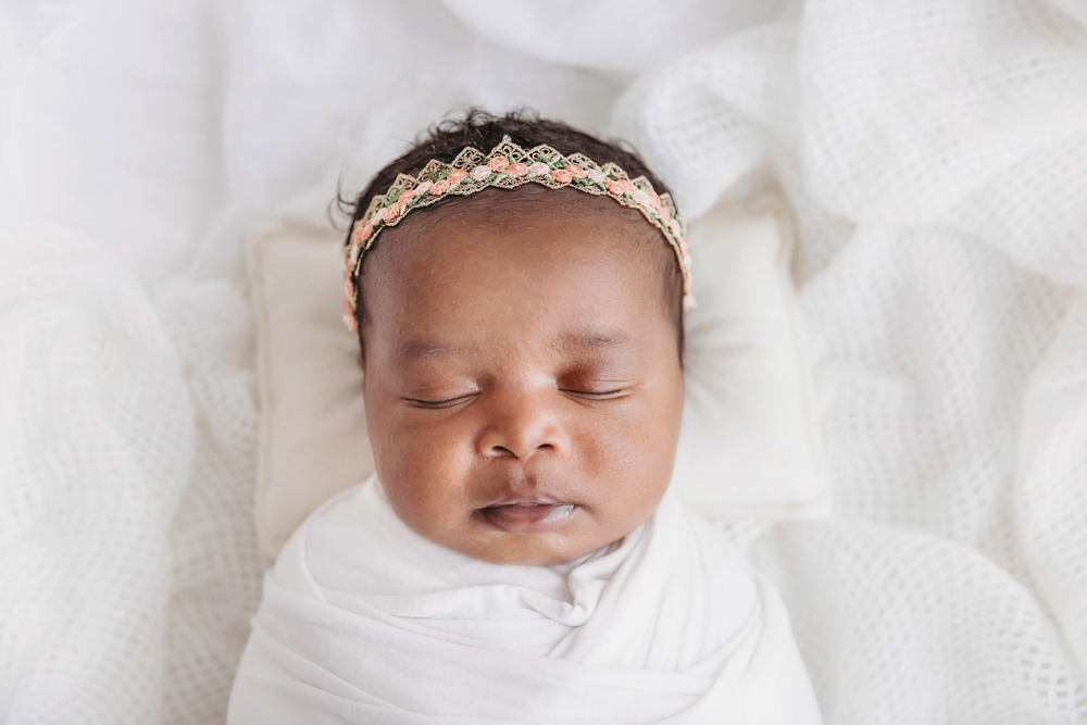 African American newborn Lily sleeping close up with lace headband and peaceful features at Reflection Images by Tracy Rowell in Florence SC