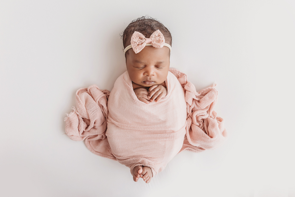 Newborn Lily overhead portrait in blush wrap, hands tucked neatly beneath chin at Reflection Images by Tracy Rowell in Florence SC