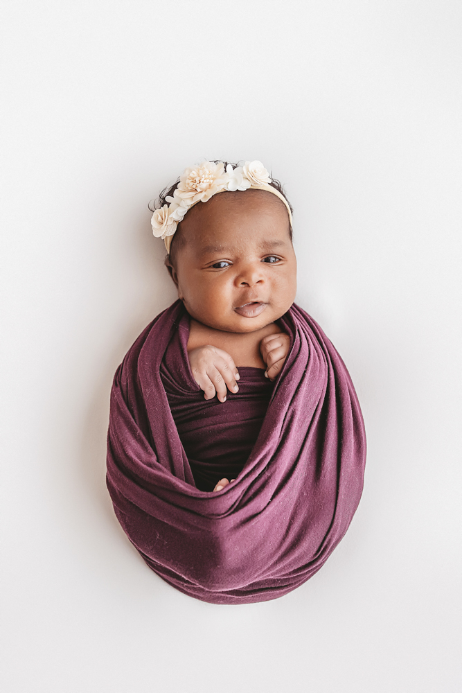 Newborn Lily front facing portrait in plum wrap, alert eyes peeking out at Reflection Images by Tracy Rowell in Florence SC