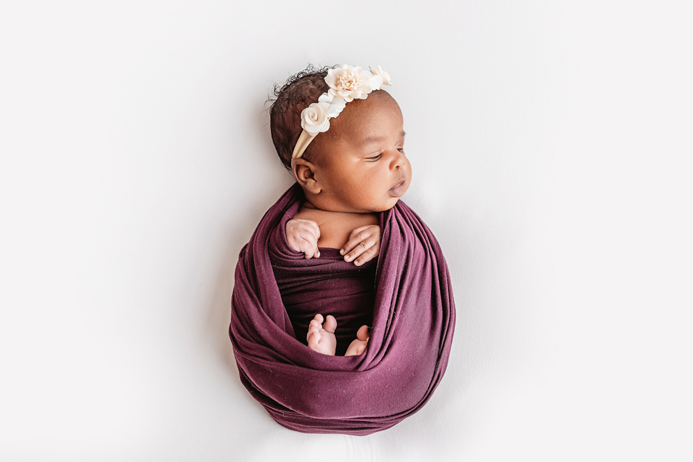Newborn Lily profile portrait in rich plum wrap with floral crown details at Reflection Images by Tracy Rowell in Florence SC