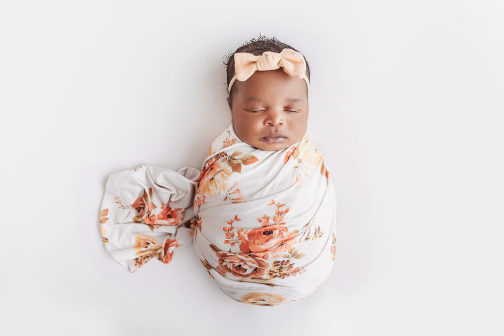 African American newborn Lily overhead portrait on white with floral wrap and matching bow at Reflection Images by Tracy Rowell in Florence SC