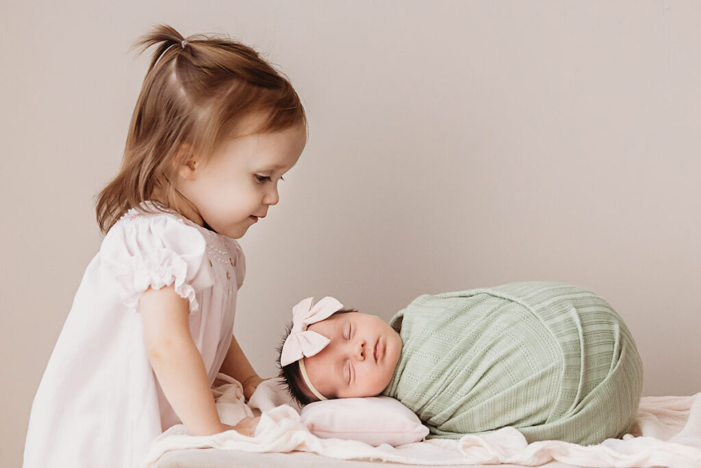 big sister looking at new baby sister