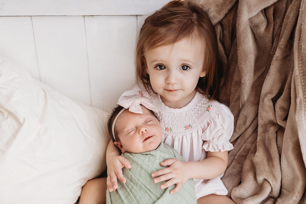 big sister holding new baby sister