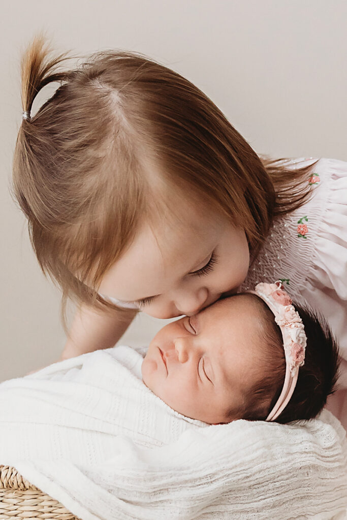 big sister kissing baby sister