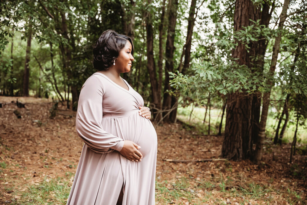 Side profile of Chelsea holding belly, trees and pine needles in Florence SC