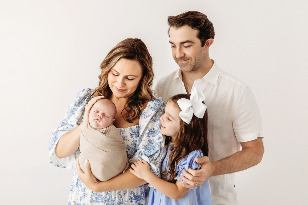 Intimate moment as Beau is cradled by mom while dad and big sister look on under soft natural light at Reflection Images by Tracy Rowell in Florence SC