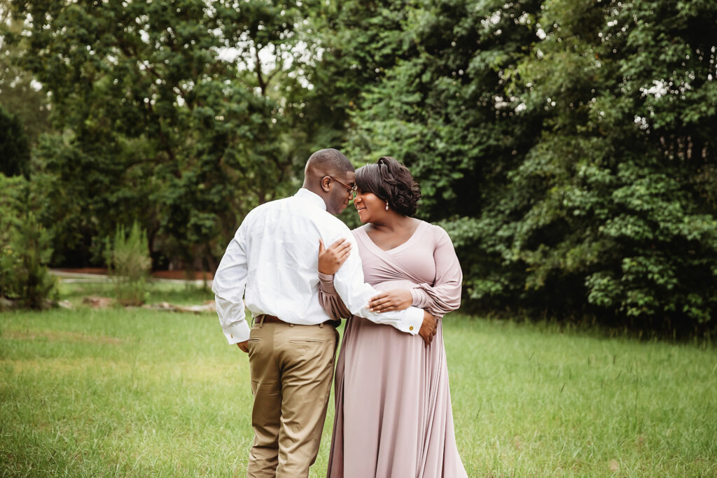 Back hug and nuzzle while walking, trees behind, mauve dress draping in Florence SC
