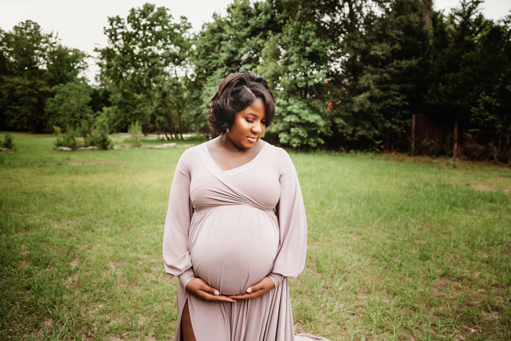 Chelsea smiling down, holding belly, mauve gown slit, open field near Florence SC