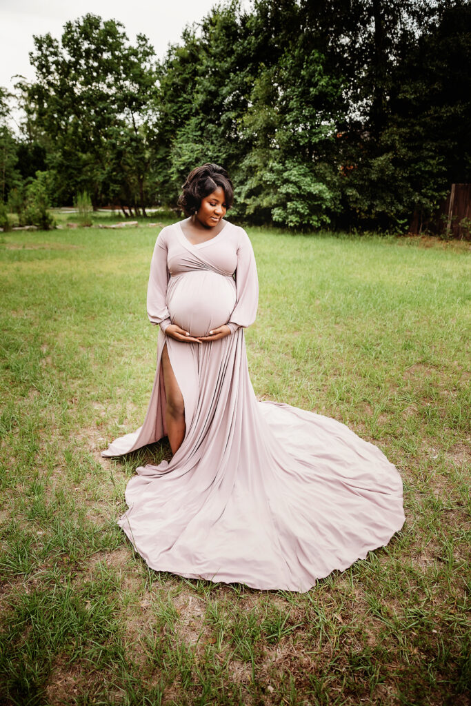 Full length portrait of Chelsea holding her belly, gown train spread in an open field in Florence SC.