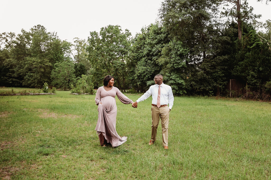 Wide view of couple strolling through the meadow, evergreens behind in Florence SC.