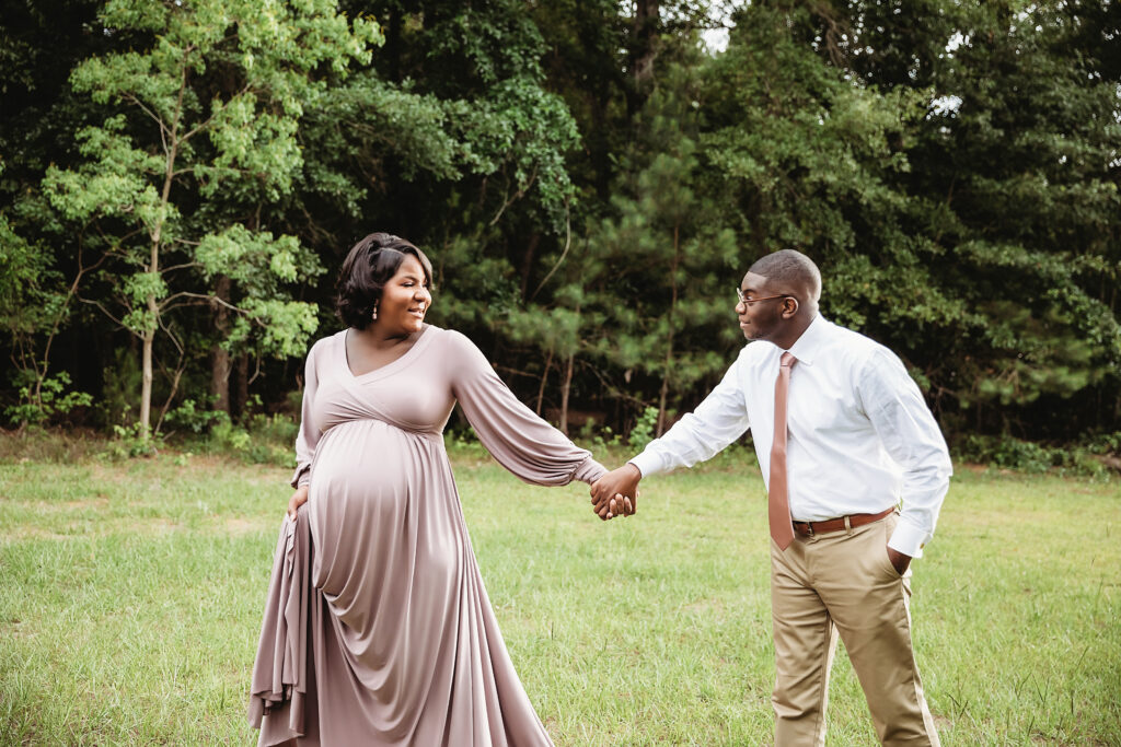 Couple walking hand in hand, smiling in a grassy field at Reflection Images by Tracy Rowell in Florence SC.