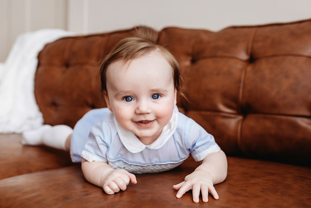 Close-up of baby boy with blue eyes in smocked romper, newborn photographer near Florence SC