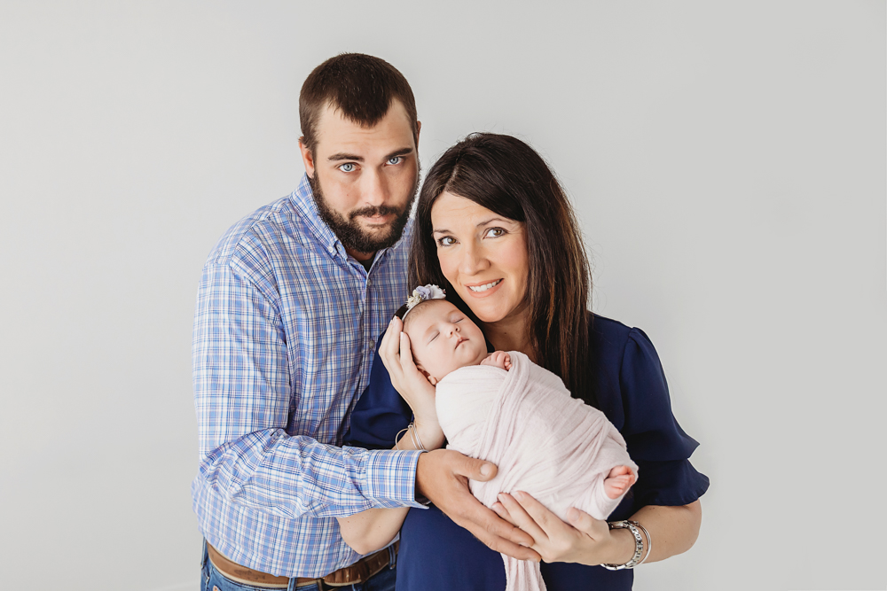 Mary Katherine cradled in moms arms while parents smile at the camera during their newborn session at Reflection Images by Tracy Rowell in Florence SC