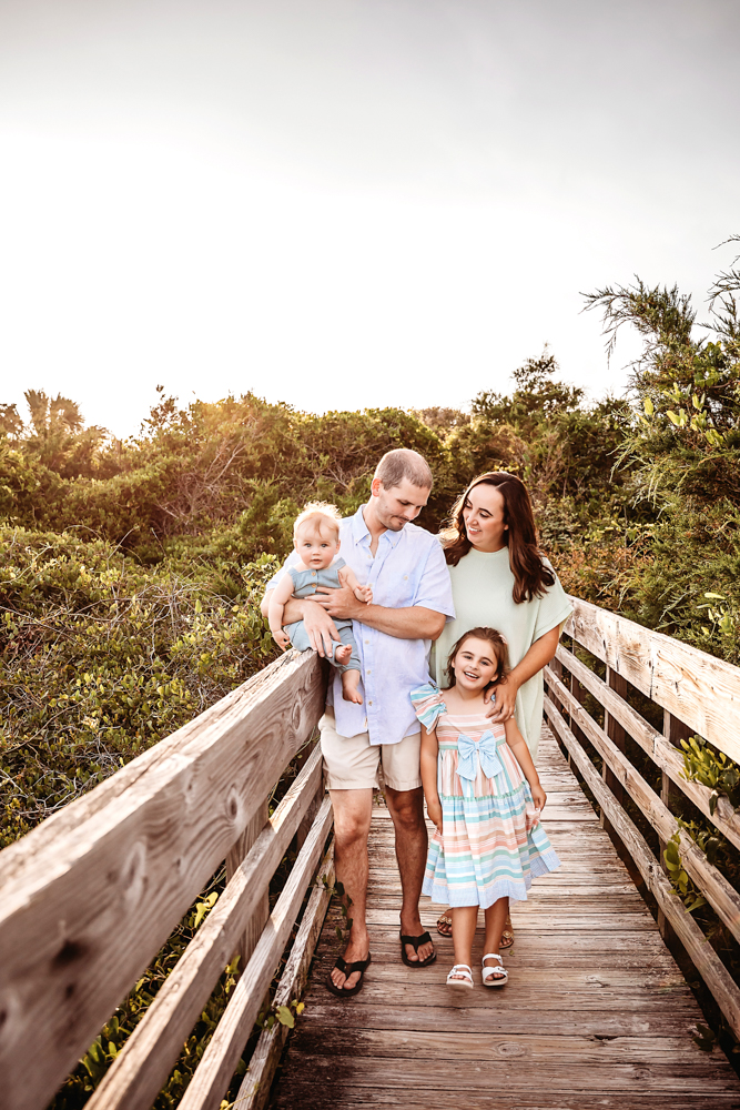 The Skinner family laughing and walking together on a sunny boardwalk surrounded by greenery at Reflection Images by Tracy Rowell in Florence SC