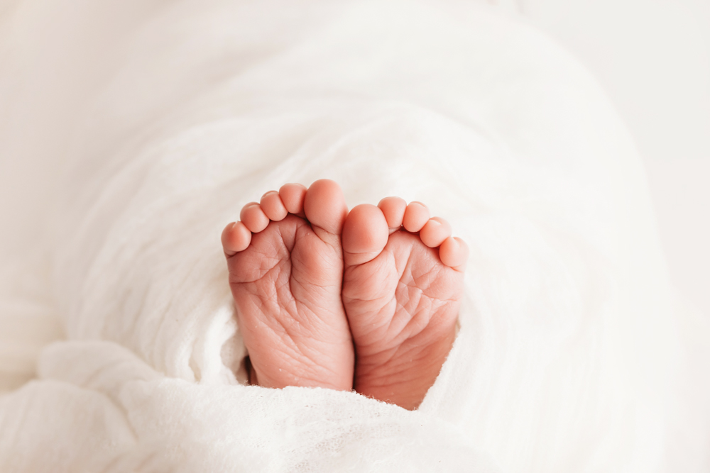 Macro closeup of newborn toes peeking from white wrap at Reflection Images by Tracy Rowell in Florence SC.