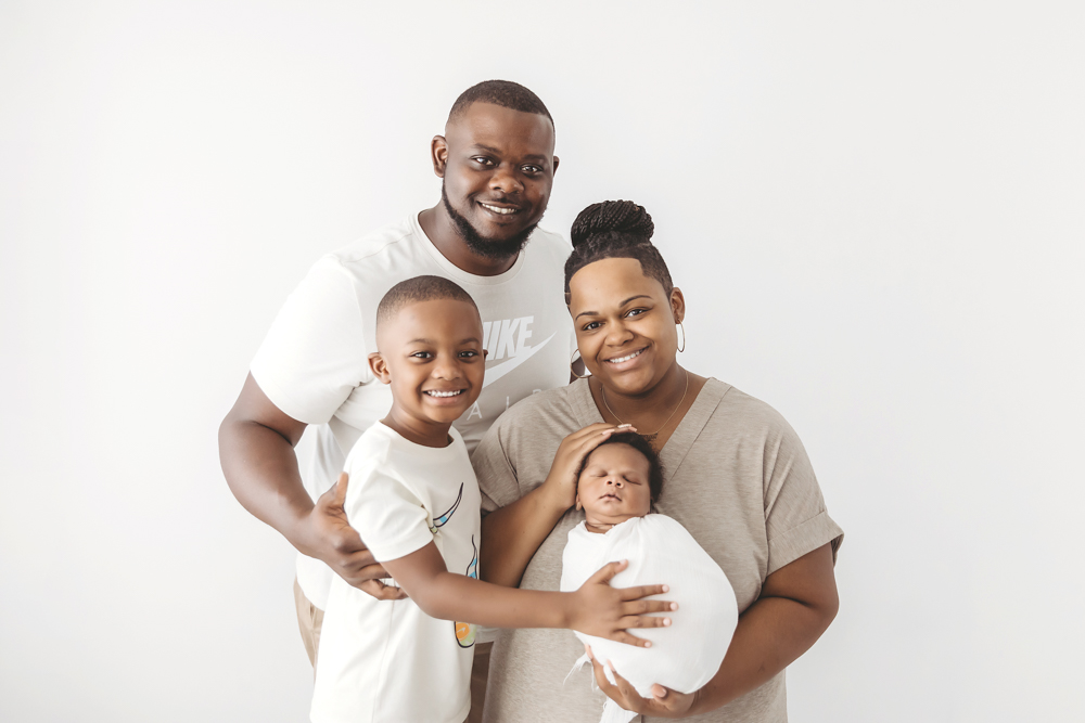 Family portrait with Braylen swaddled in white, held close by mom, dad, and big brother at Reflection Images by Tracy Rowell in Florence SC