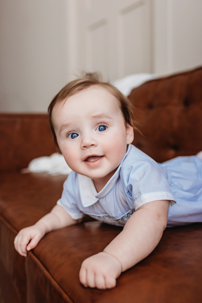 Happy baby smiling during tummy time on couch, milestone session near Florence SC