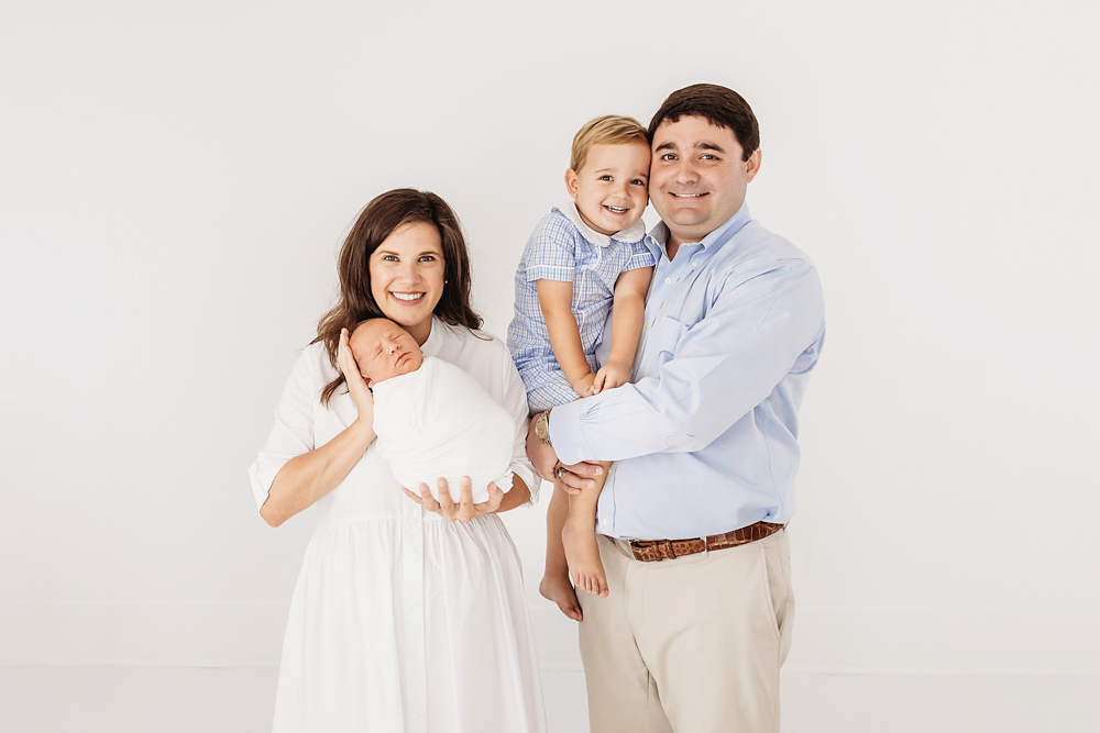 Full family portrait with baby Harry, Tommy, and parents Rhett and Eliza standing together smiling at Reflection Images by Tracy Rowell in Florence SC