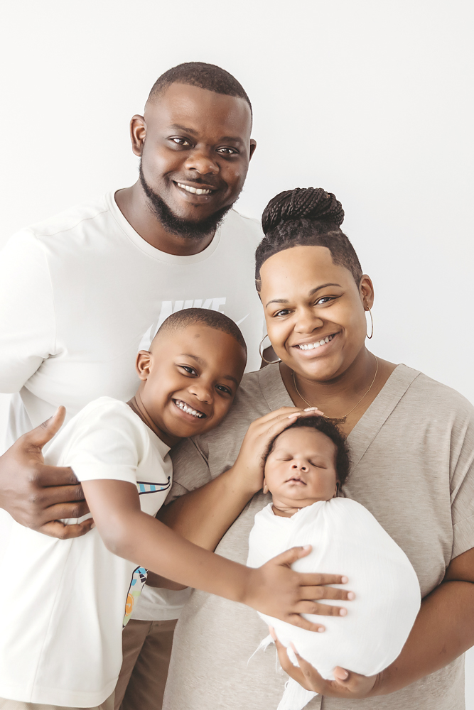 Braylen wrapped in white and cradled securely in dads hands, standing against a white studio backdrop at Reflection Images by Tracy Rowell in Florence SC