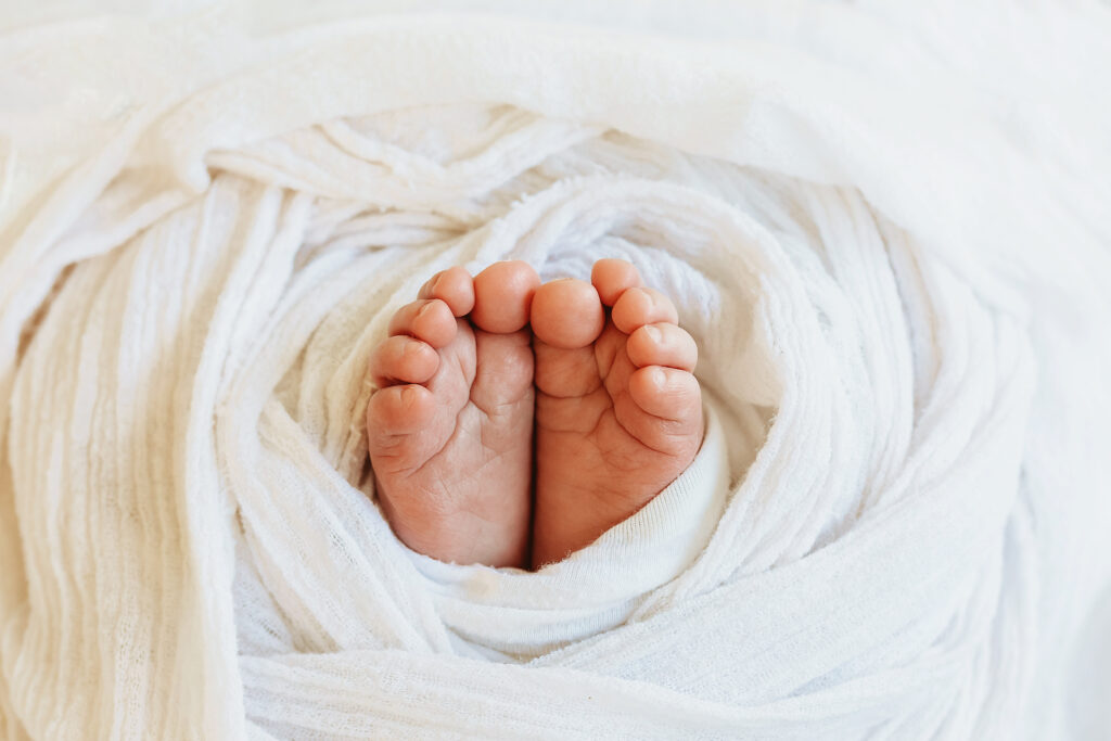 Macro close-up of baby toes tucked in soft white muslin wrap at Reflection Images by Tracy Rowell in Florence SC