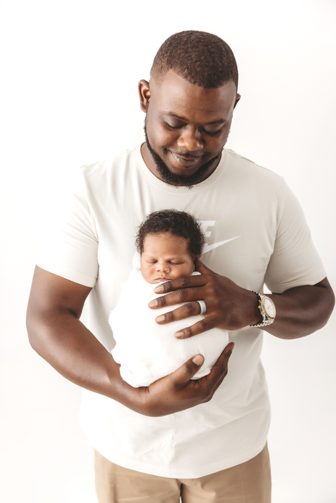 Big brother kissing baby Braylens forehead while held by mom and dad in soft studio lighting at Reflection Images by Tracy Rowell in Florence SC