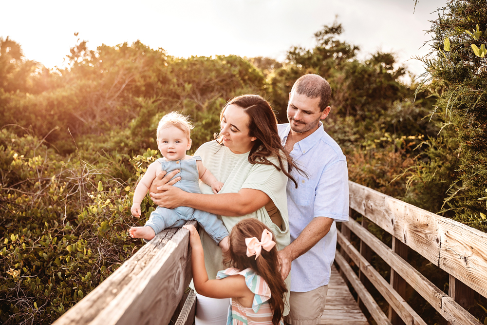 The Skinner family gathered close as baby Cole sits up on the boardwalk rail during a sunset session at Reflection Images by Tracy Rowell in Florence SC