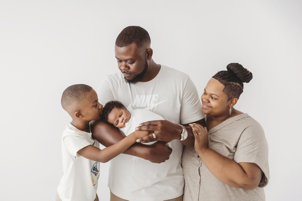 Dad holding Braylen wrapped in white swaddle, looking down tenderly in the Florence SC studio at Reflection Images by Tracy Rowell