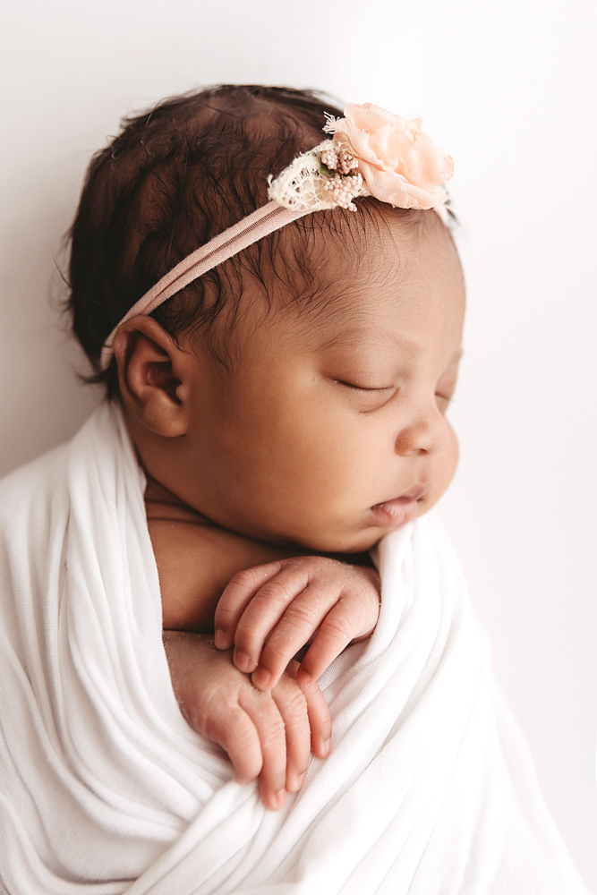 Profile close-up of Harlem in a white wrap wearing a peach floral headband, peacefully sleeping at Reflection Images by Tracy Rowell in Florence SC