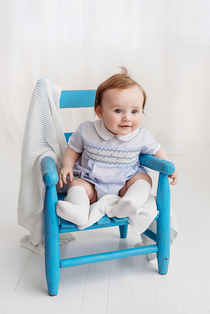 Baby boy in blue outfit seated in vintage chair, Reflection Images by Tracy Rowell studio portraits