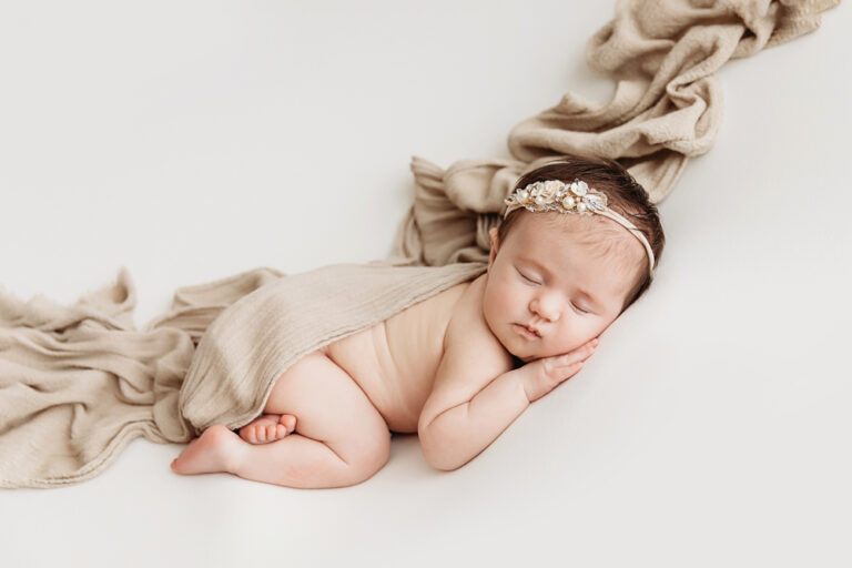Side-lying pose of Mary Katherine under a flowing taupe muslin drape with a jeweled headband at Reflection Images by Tracy Rowell in Florence SC
