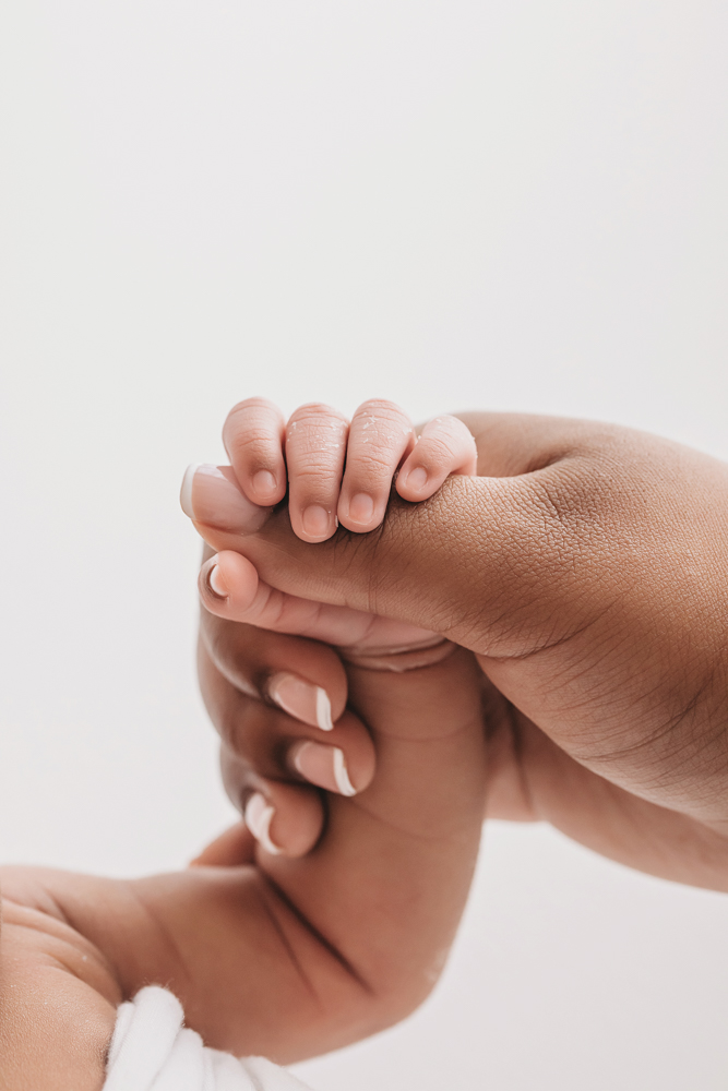 Close-up of Harlems tiny hand gently holding onto moms finger, sweet newborn detail captured at Reflection Images by Tracy Rowell in Florence SC