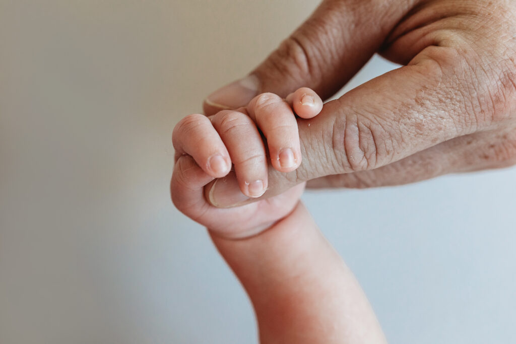 Newborn holding dads finger, showing gentle grip and soft natural tones at Reflection Images by Tracy Rowell in Florence SC