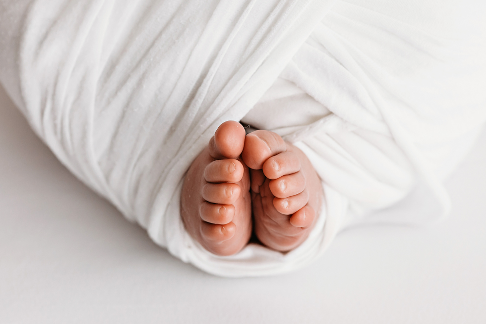 Macro close-up of newborn Listons toes peeking out of a white swaddle at Reflection Images by Tracy Rowell in Florence SC