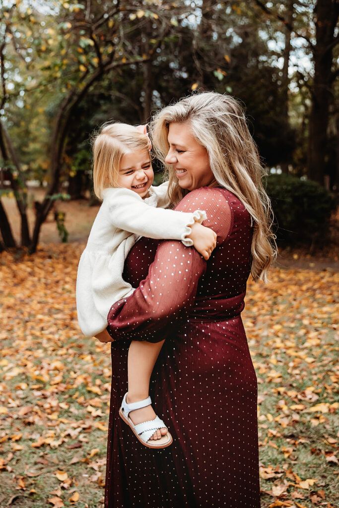 Sweet moment of mom and daughter nose-to-nose, laughing together under colorful fall foliage in Florence SC