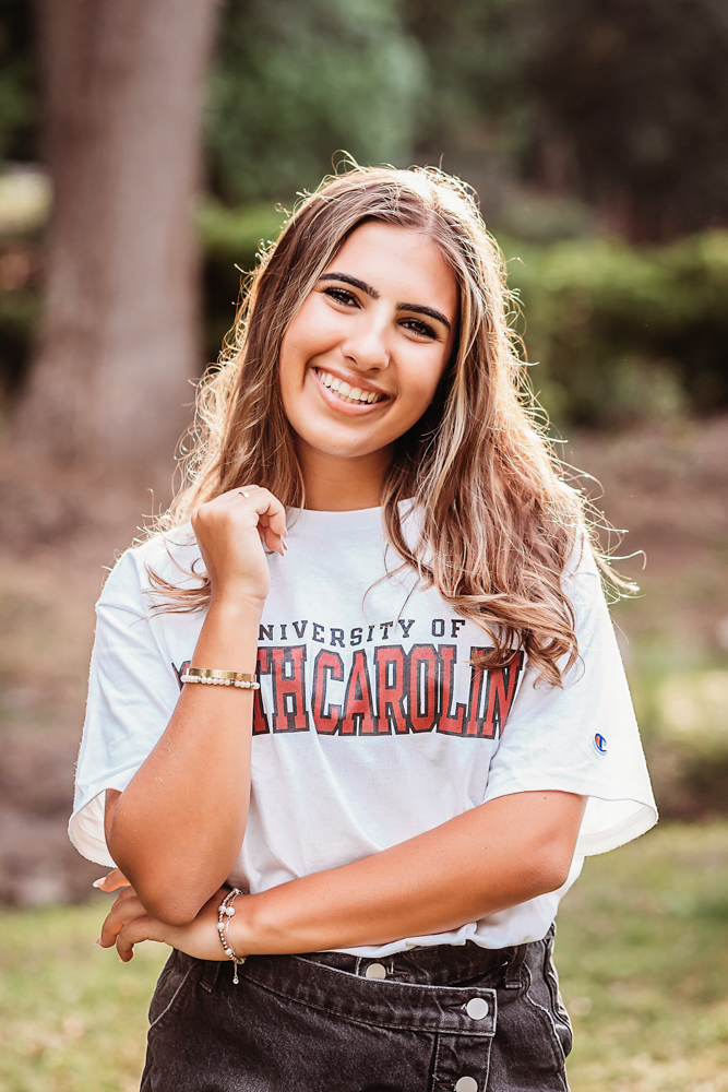 rustic bridge at golden hour, showing a standing pose in USC shirt and denim skirt from a close-up angle at Reflection Images by Tracy Rowell in Florence SC.