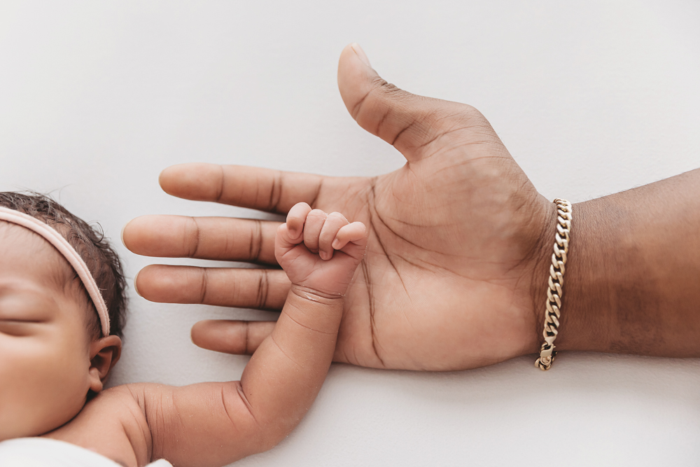 Close-up of Harlems tiny hand holding onto dads finger, tender newborn moment at Reflection Images by Tracy Rowell in Florence SC