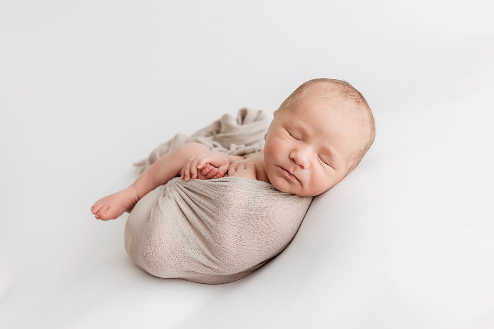 Harry swaddled in taupe wrap lying on his side with toes and fingers visible at Reflection Images by Tracy Rowell in Florence SC