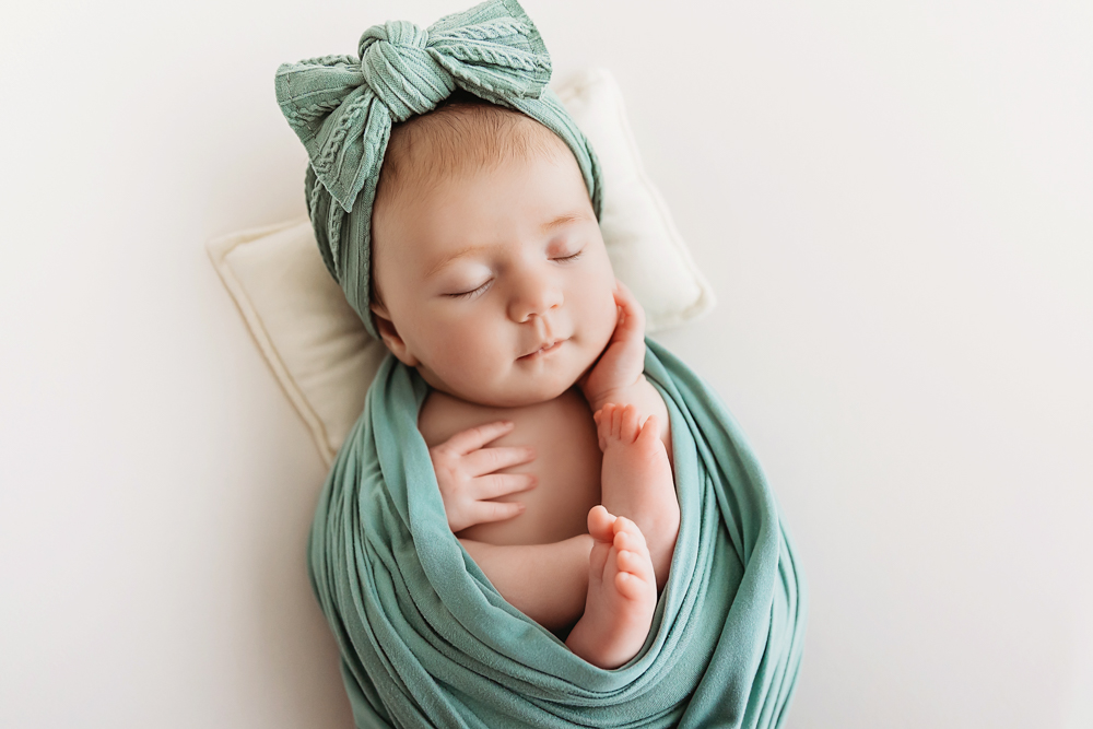 Mary Katherine in a teal wrap with matching bow turban posed on a tiny pillow in studio light at Reflection Images by Tracy Rowell in Florence SC