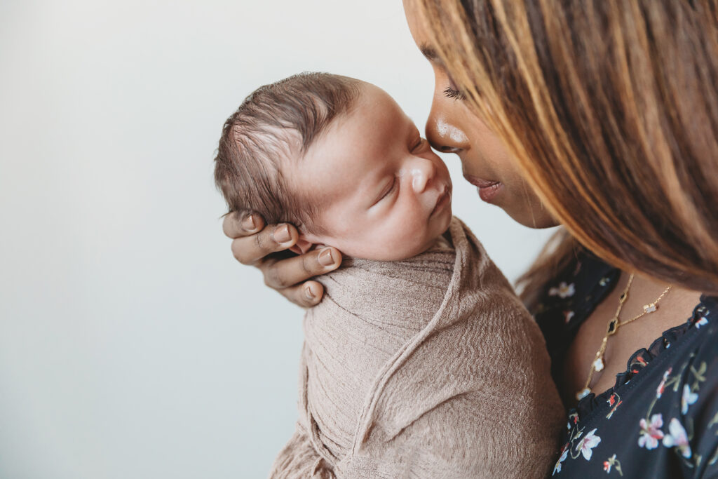 Mom gently nuzzling her swaddled newborn wrapped in a textured brown blanket at Reflection Images by Tracy Rowell in Florence SC