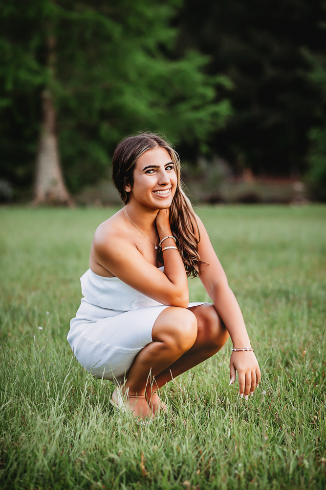 open field at golden hour, showing a sitting pose in floral dress from a full-body angle at Reflection Images by Tracy Rowell in Florence SC.