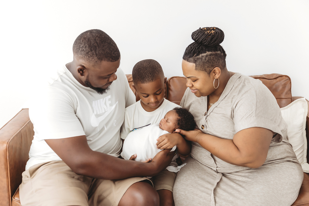 Big brother kissing newborn Braylen on the nose, both cozy in soft white swaddle at Reflection Images by Tracy Rowell in Florence SC
