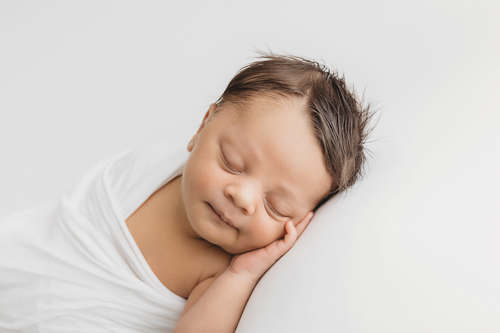 Liston sleeping on his side with hand tucked under cheek and subtle smile on white backdrop at Reflection Images by Tracy Rowell in Florence SC