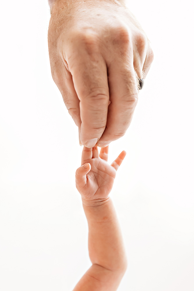 Baby grasping dads finger in upright pose at Reflection Images by Tracy Rowell in Florence SC.