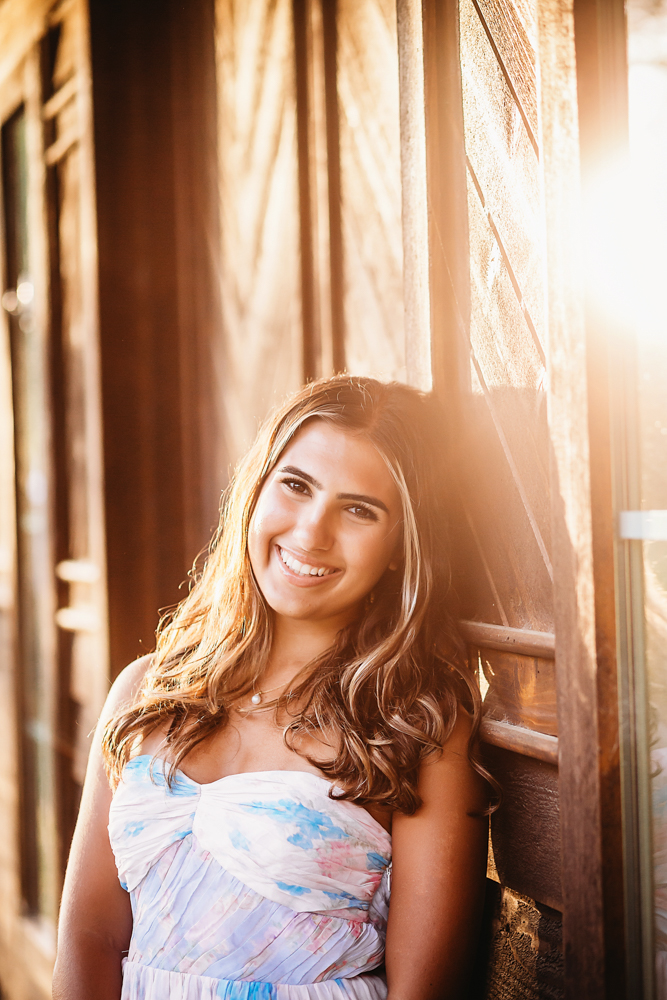golden hour at golden hour, showing a smiling pose in white boots from a over-the-shoulder angle at Reflection Images by Tracy Rowell in Florence SC.