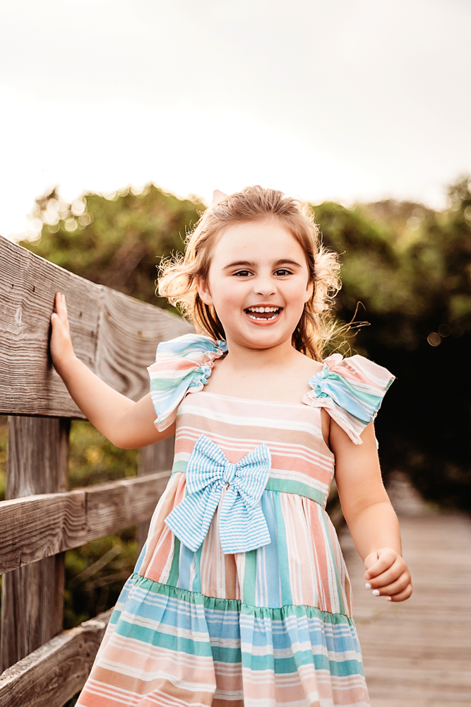 Candid of Stella laughing in a striped pastel dress on a sunlit boardwalk at Reflection Images by Tracy Rowell in Florence SC